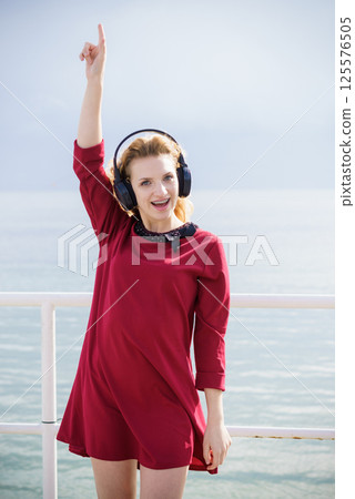 Happy woman wearing headphones outdoor 125576505
