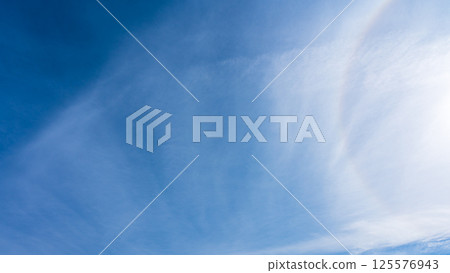 薄薄的雲朵在藍天中飄動,太陽周圍形成一道彩虹 薄薄的雲朵在藍天中飄動,太陽周圍形成一道彩虹 125576943