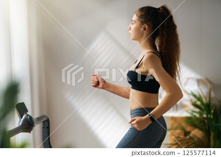 Young woman running on a treadmill indoors 125577114