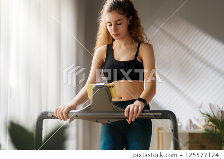 Young woman running on a treadmill indoors Young woman running on a treadmill indoors 125577124