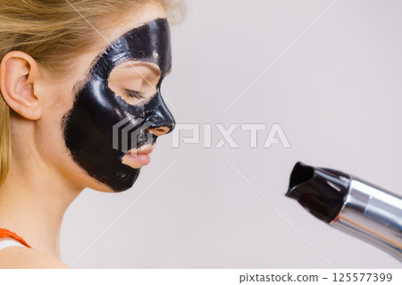 Girl drying peel-off black mask on face Girl drying peel-off black mask on face 125577399