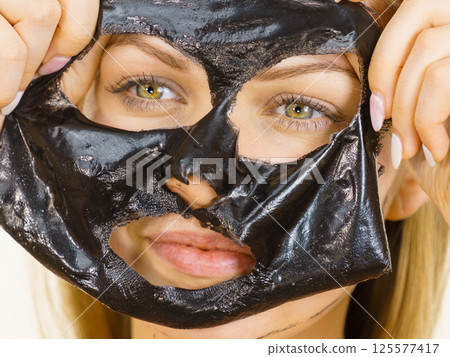 Girl removes black mask from face 125577417