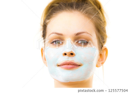 Girl apply green mud mask to face 125577504