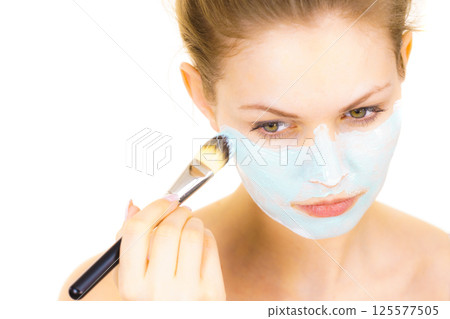 Girl apply green mud mask to face Girl apply green mud mask to face 125577505