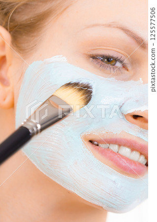 Girl apply green mud mask to face 125577506