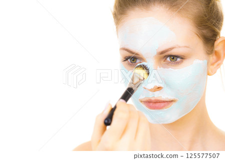 Girl apply green mud mask to face 125577507