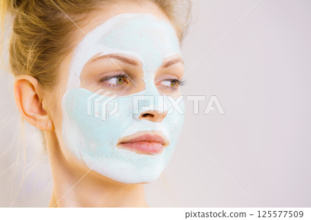 Girl with white green mud mask on face Girl with white green mud mask on face 125577509
