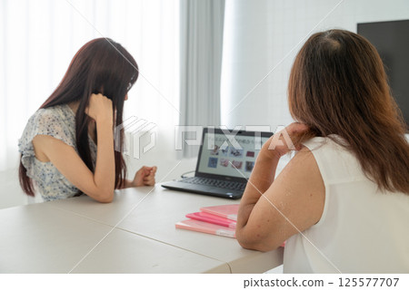 A middle-aged female advisor explaining things to a middle-aged woman using a laptop 125577707