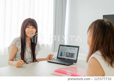 A middle-aged female advisor explaining things to a middle-aged woman using a laptop 125577710