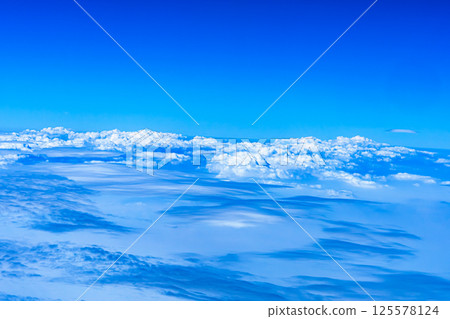 Aerial view from airplane window above green ground. View from the airplane window with beautiful clouds at sunrise. Earth and sky as seen through window of an airplane. 125578124