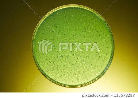 Light green liquid extracted from natural pennywort is filled in a glass petri dish. The experiment was conducted in the laboratory to modulate cosmetics and medicines. Dark yellow green background. Light green liquid extracted from natural pennywort is filled in a glass petri dish. The experiment was conducted in the laboratory to modulate cosmetics and medicines. Dark yellow green background. 125578297