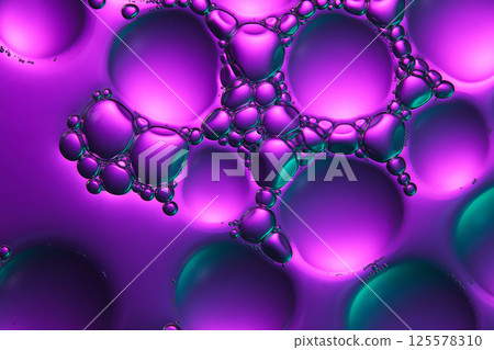 Purple, pink and green light mixed together, shining on the transparent surface of the crystal glass. Simulating the molecular structure of cosmetic solutions. Abstract cosmetic laboratory.  125578310