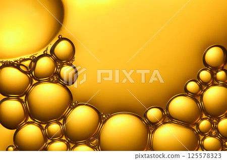Combination of dozens of tiny bubbles, connected together into a dense network, concentrated on one side of the photo. The rest is a liquid chemical solution, smooth surface, gold background.  125578323