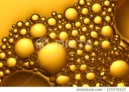Close-up of numerous bubbles closely packed together, tiny bubbles stacked on top of each other in the gap of the larger bubbles. Each bubble has an outer rim for protection. Yellow background. Close-up of numerous bubbles closely packed together, tiny bubbles stacked on top of each other in the gap of the larger bubbles. Each bubble has an outer rim for protection. Yellow background. 125578325