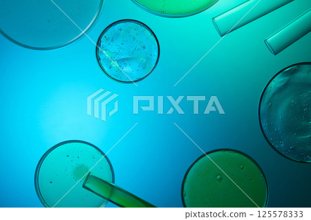 Round petri dishes containing liquid extracts from gotu kola and aloe vera. Glass tubes are pouring the liquid from above into the petri dishes below. Laboratory equipment used in research. Round petri dishes containing liquid extracts from gotu kola and aloe vera. Glass tubes are pouring the liquid from above into the petri dishes below. Laboratory equipment used in research. 125578333