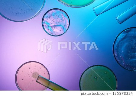 Blue and pink gradient background with petri dishes displayed on top. Thick cosmetic essence with numerous bubbles floating on the surface. Test tubes placed around, laboratory research concept. 125578334