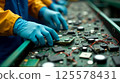 Gloved hands meticulously sort through electronic waste on a conveyor belt at a recycling facility. 125578431