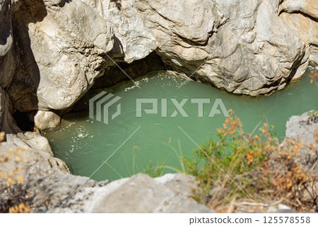 Small water source between rocks exposed to the sun 125578558