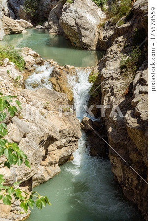 Small waterfall of a stream in sunny nature 125578559