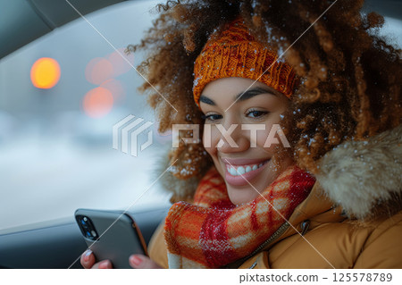 Latin woman with curly hair is smiling and holding cell phone at car Latin woman with curly hair is smiling and holding cell phone at car 125578789