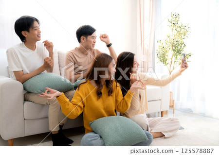 Group young asian friends sitting on sofa taking a selfie or video call using smart phone. Group young asian friends sitting on sofa taking a selfie or video call using smart phone. 125578887