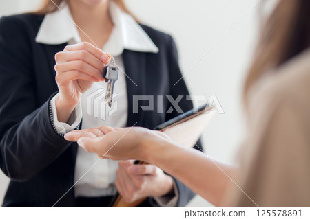 Closeup hands real estate agent giving house key with couple after success property purchase home. Closeup hands real estate agent giving house key with couple after success property purchase home. 125578891