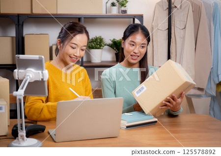 Two young asian woman working while planning online business and checking order. 125578892