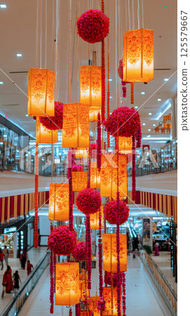 Elegant Interior Decor in Shopping Mall with Orange Lanterns and Pink Floral Arrangements. Concept of Modern Design, Festive Atmosphere, Creative Lighting. Vertical 125579667
