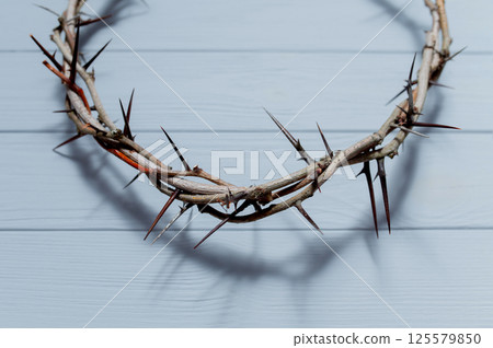 Wooden wall casting dark shadow from Jesus crown of thorns, symbolizing religious suffering and sacrifice Christian background Easter concept 125579850