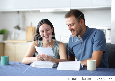 Happy interracial couple holding bank statement 125580467