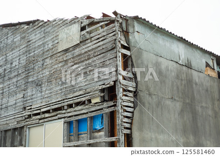 The exterior wall of an old, dilapidated warehouse 125581460