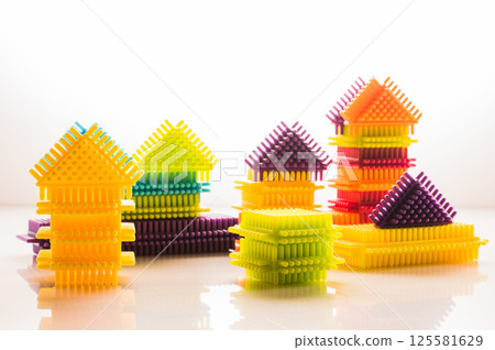 Bright colorful elements of a children's construction set are laid out on a white background, creating a lively and dynamic composition. Bright colorful elements of a children's construction set are laid out on a white background, creating a lively and dynamic composition. 125581629