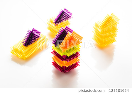 The elements of the children's construction set are presented in a full range of vibrant colors. The play-constructor parts are placed on a white background, creating a contrasting composition. 125581634