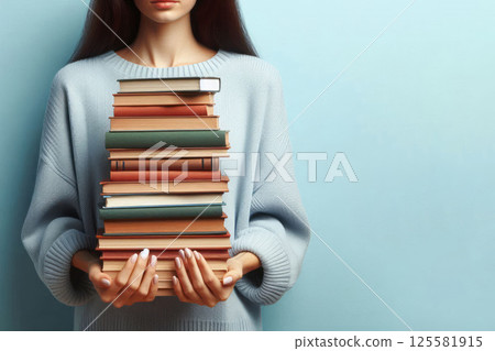 A girl with a large stack of books in her hands. Space for text. 125581915