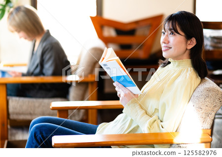 Young woman relaxing on the sofa and reading a book 125582976