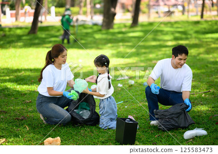 Parents and child volunteering together by collecting trash and cleaning up a park 125583473