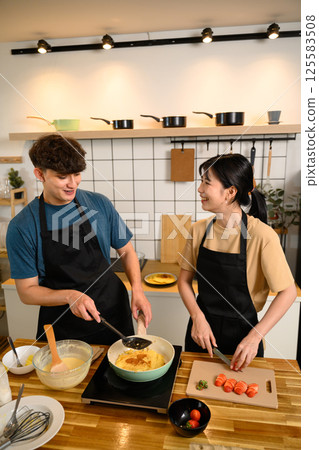 Smiling couple cooking breakfast together in the kitchen 125583508