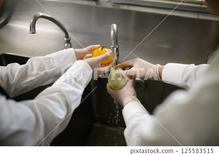 Close up of hands washing fresh vegetables during cooking class 125583515