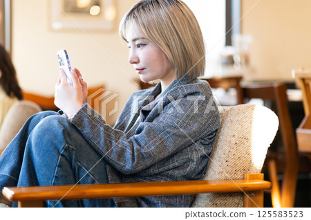 年輕女子在沙發上放鬆並拿著智慧型手機 125583523