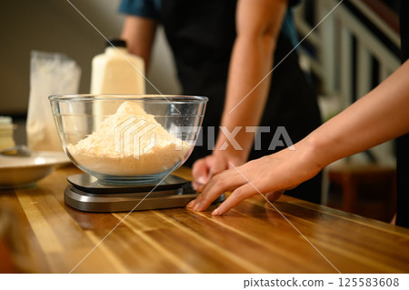 Close up of couple measuring flour for homemade pancakes in a cozy kitchen 125583608