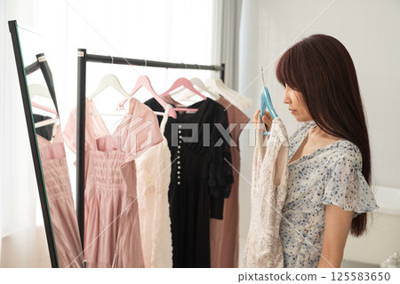 A woman choosing clothes hanging on a hanger rack A woman choosing clothes hanging on a hanger rack 125583650