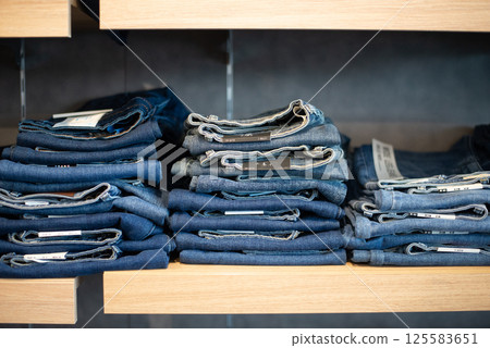 Many jeans in closet. Stack of jeans on shelf. Concept of buy , sell , shopping and jeans fashion . Many jeans in closet. Stack of jeans on shelf. Concept of buy , sell , shopping and jeans fashion . 125583651