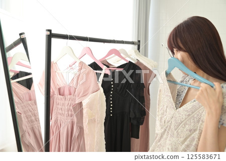 一位女士正在挑選掛在衣架上的衣服 125583671