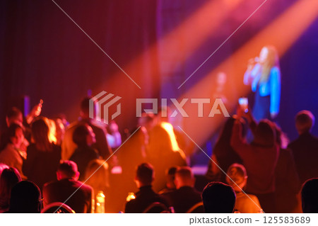 Colorful concert crowd blurred in warm stage lights at live performance 125583689