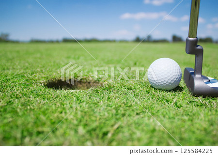 A golf ball is putted with a golf club 125584225