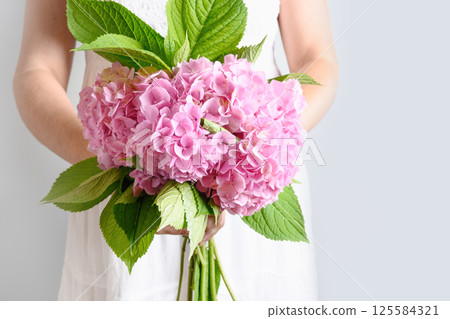 Bouquet of fresh pink hydrangea flower woman hands. Flowers delivery. Floral shop concept. Fresh bouquet. Wedding banner. Bouquet of fresh pink hydrangea flower woman hands. Flowers delivery. Floral shop concept. Fresh bouquet. Wedding banner. 125584321
