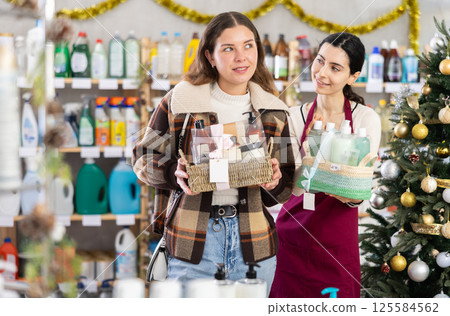 seller offers a woman a bath milking set against the background of a Christmas tree seller offers a woman a bath milking set against the background of a Christmas tree 125584562