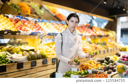 Young woman choosing lime in vegetable shop 125584735