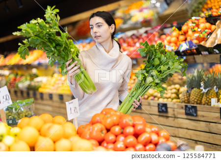 In vegetable store, young woman customer buy celery In vegetable store, young woman customer buy celery 125584771