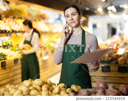 Female owner of vegetable store analyzes documents, reads report Female owner of vegetable store analyzes documents, reads report 125584859